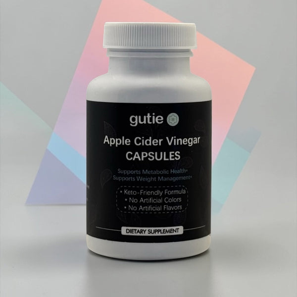 Bottle of gutie Apple Cider Vinegar Capsules on a gray background with geometric shapes.